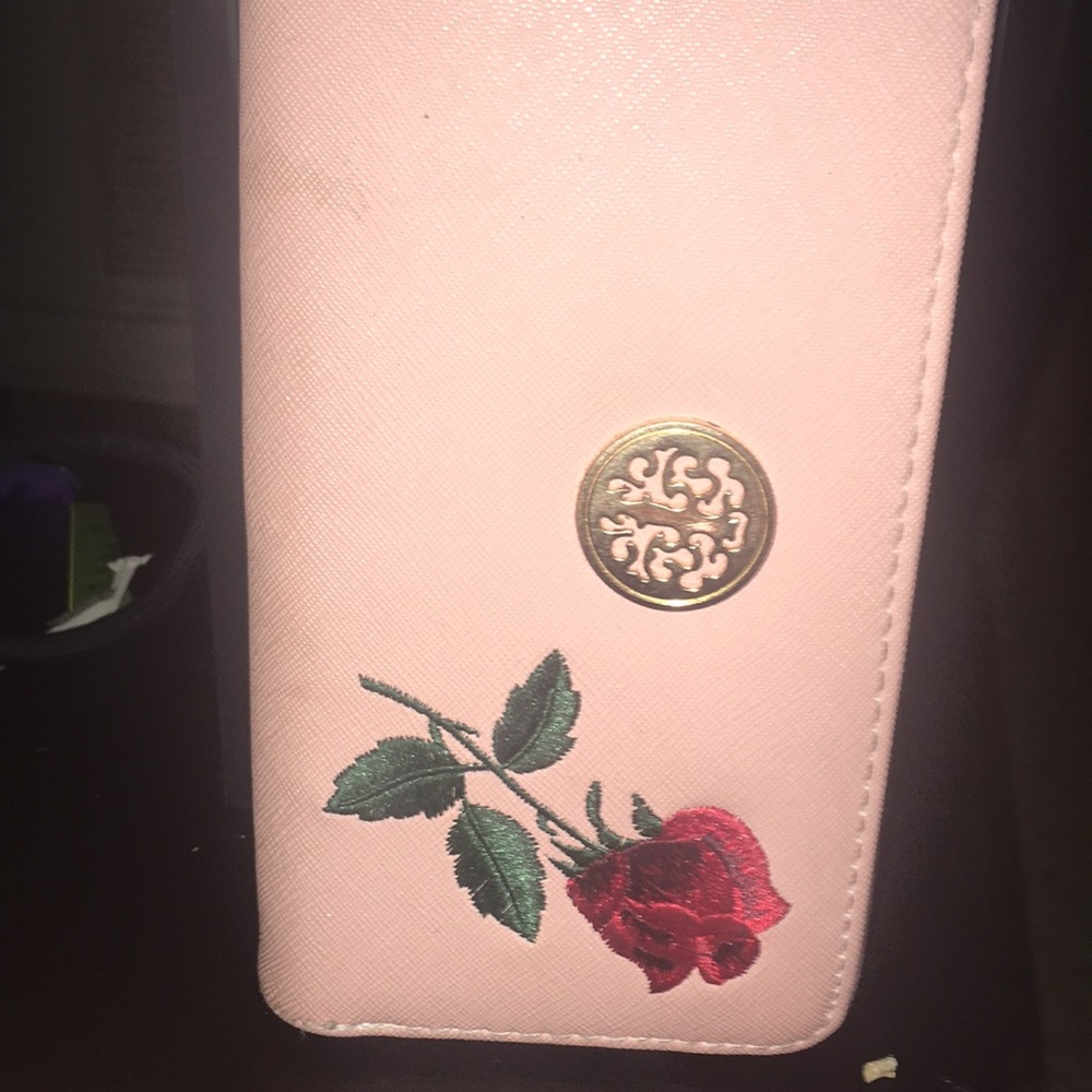 A pink wallet with rose designs.